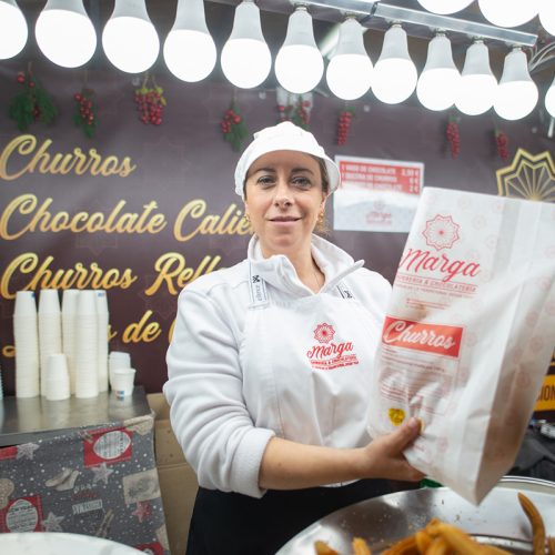 Churrería Marga mostrando una bolsa de churros en el mercado de Navidad de Valladolid