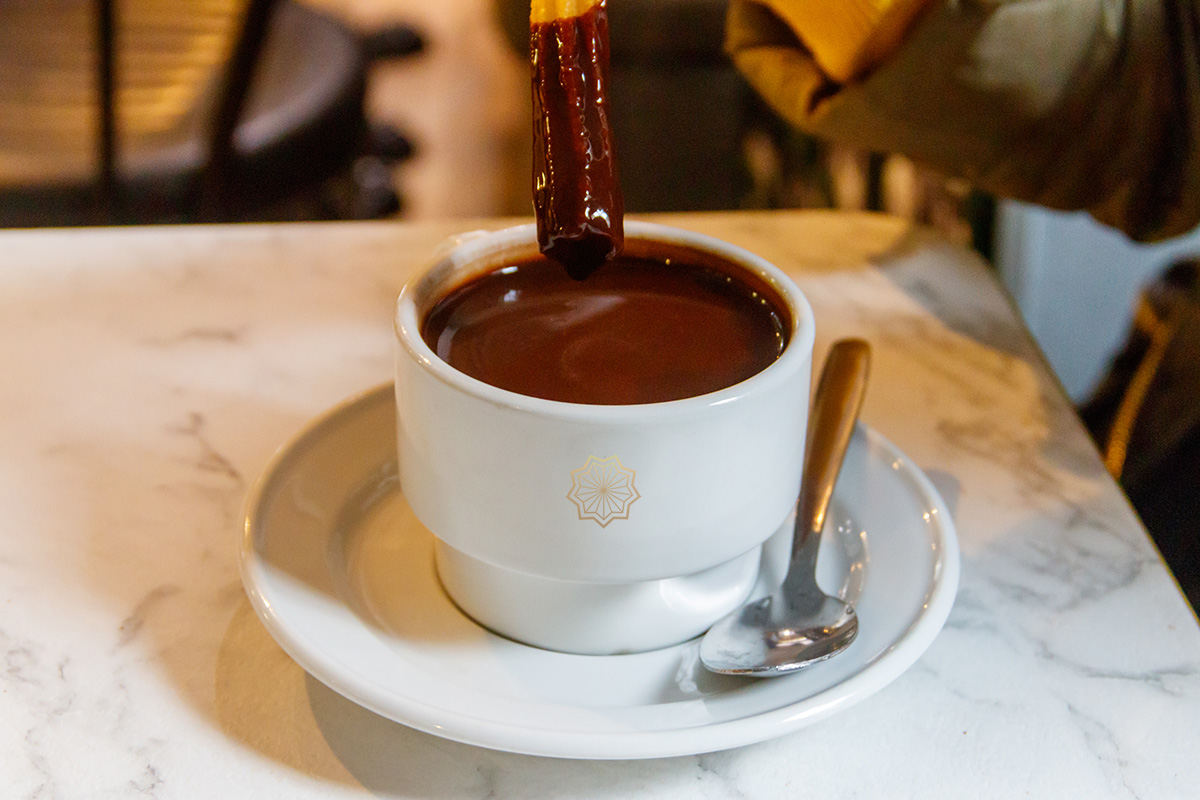 Taza de chocolate caliente con churro en Churrería Marga en Valladolid